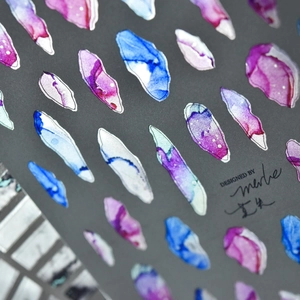 Macro detail of watercolor marble nail stickers with silver foil edges and abstract patterns