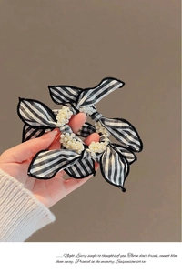 Close-up of black and white striped bow scrunchie with elegant pearl cluster accents