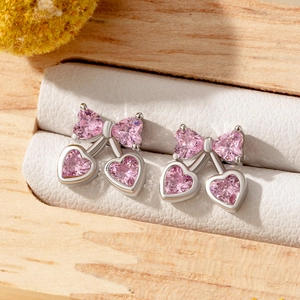 Pink bow cherry stud earrings in titanium steel displayed on white jewelry box lining