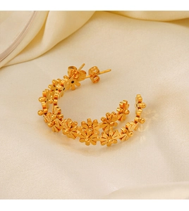 Gros plan de boucles d'oreilles créoles fleurs en acier doré 18K sur tissu