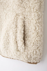 Vue détaillée du tissu en peau de mouton beige avec bordure marron sur le gilet femme