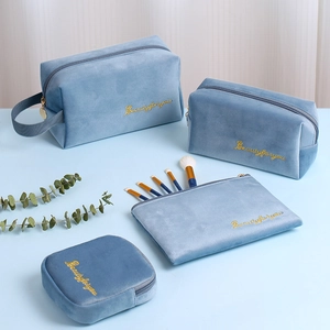 Detailed set of four blue velvet cosmetic bags with gold embroidery and various sizes