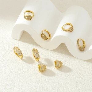 Macro view of gold hoop earrings with sparkling zircon inlay on white wavy stands
