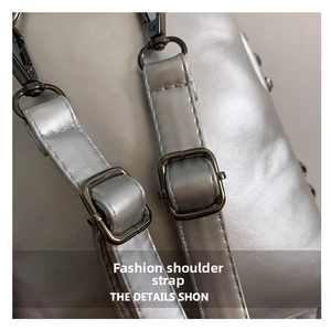 Macro detail of silver PU leather backpack strap with gun-black metal buckles and rivets