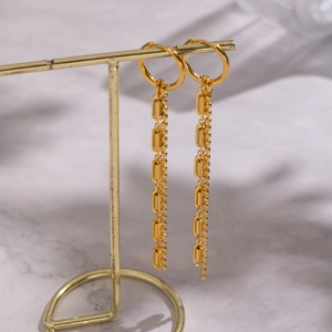 Elegant 18K gold-plated geometric long tassel earrings on a minimalist display