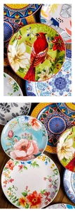 Flat lay of colorful ceramic plates with floral and bird patterns on a wooden table