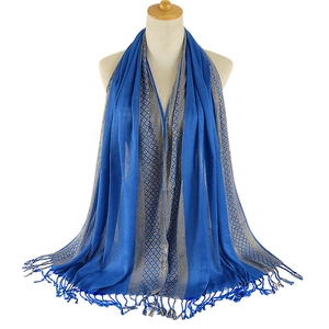 Blue tassel shawl with silver geometric pattern on mannequin in a minimalist studio setting