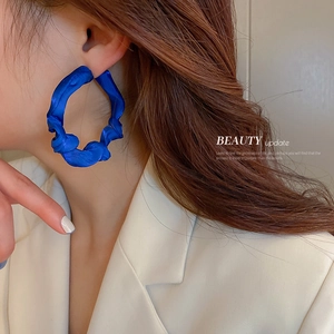 Fashionable klein blue fabric wrapped geometric hoop earrings worn by a model