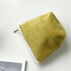 Detailed shot of mustard yellow corduroy makeup bag with soft textured stripes and zipper