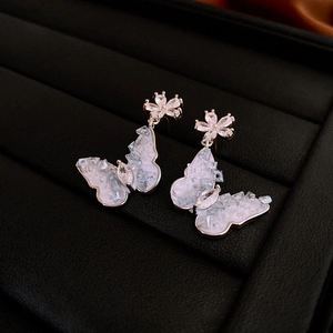 Detailed close-up of butterfly stud earrings with purple zircons in a black jewelry box