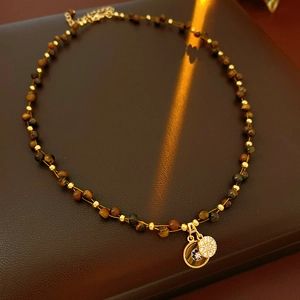 Detailed view of tiger eye stone necklace with gold zircon double circular pendant on leather
