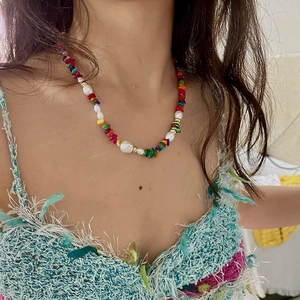 Détail d'un collier choker doré bohème avec perles d'eau douce et pierres colorées