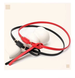 Close-up of elegant black and red leather waist belts with interlocking gold buckles
