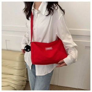 Détail d'un sac à bandoulière rouge en tissu Oxford avec un charmant porte-clés peluche