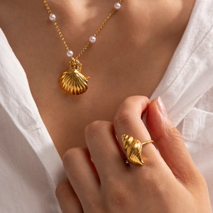 Close-up of a model wearing a gold shell pendant necklace and matching starfish ring set