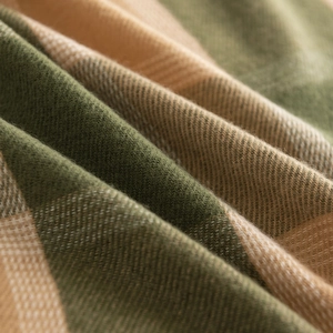 Macro shot of soft green and beige plaid cashmere-like fabric showing weave texture