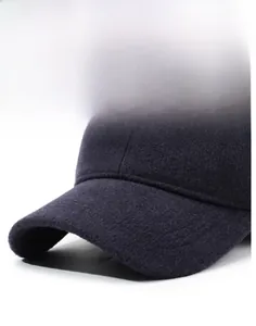 Makrodetail einer dunklen Woll-Wintermütze mit Metalllogo und strukturierter Stoffoberfläche