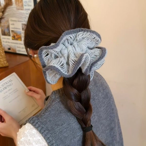Detail of grey knitted double-layered flower scrunchie on a braided ponytail hairstyle