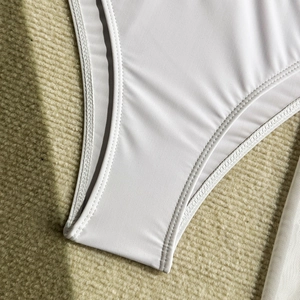 Dettaglio del costume bianco con doppia cucitura rinforzata e texture del tessuto elastico
