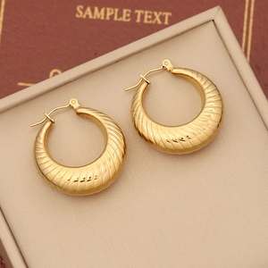 Macro view of gold croissant hoop earrings with ribbed texture on a jewelry display mat
