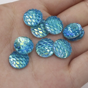Macro detail of blue iridescent fish scale resin cabochons held in palm for DIY crafts