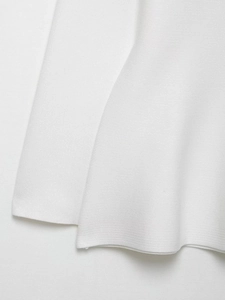 Close-up detail of white knitted fabric texture and ribbed hem on spring cardigan