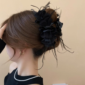 Detail of elegant black multi-layered feather flower hair claw on brunette hair