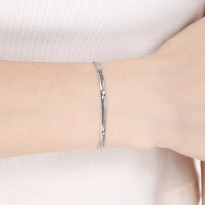 Minimalist silver herringbone snake chain bracelet worn on wrist with knitwear background