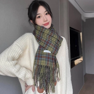 Green and brown plaid cashmere-like scarf with tassels, modeled in a warm setting