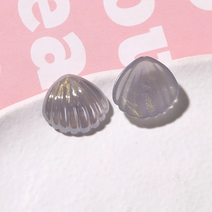 Dettaglio di ciondoli a conchiglia in resina viola con glitter dorati per il fai-da-te