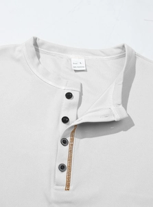 Detail of white polo shirt collar with buttons and waffle knit texture on marble surface