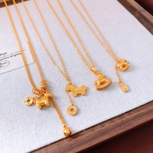 Close-up of gold-plated horse pendants with adjustable chains on a textured cream fabric