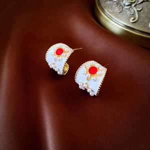 Gros plan de boucles d'oreilles vintage en forme de C avec émail blanc et perles