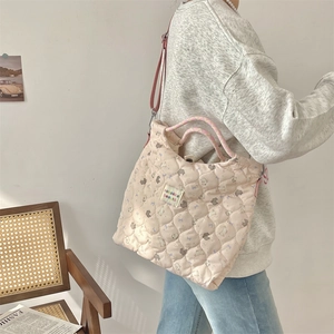 Detail of pink quilted crossbody bag with cartoon prints and rainbow woven handle