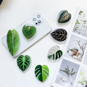 Macro detail of glossy monstera and tropical leaf phone griptoks on a white phone