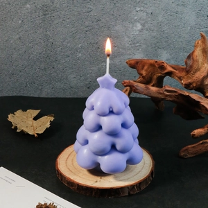 Close-up of a lit purple Christmas tree candle with star on wood base decor