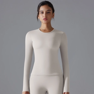 Front view of beige long sleeve yoga top and tight leggings set on professional model