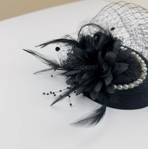 Close-up of black vintage fascinator with mesh veil, feathers and faux pearls