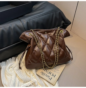 Detail of quilted brown chain bucket bag featuring gold hardware and drawstring closure
