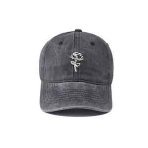 Close-up of white rose embroidery on vintage washed grey denim baseball cap