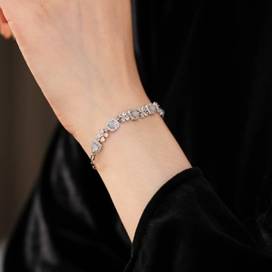 Vue macro d'un bracelet fleur en zircon argenté sur poignet et velours noir