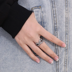 Minimalist silver infinity ring with white zircon stones worn on model hand with denim background