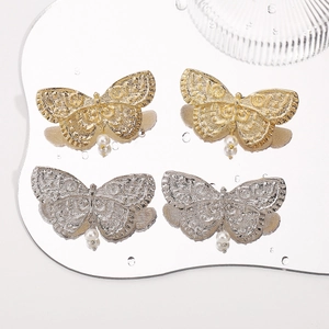 Vintage butterfly pearl drop earrings in gold and silver finish on reflective surface