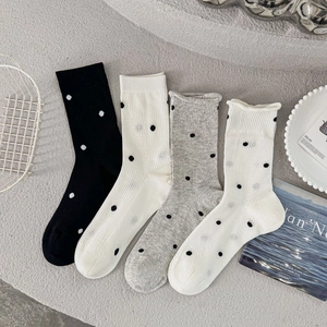 Detail of four pairs of breathable polka dot crew socks in black, white, and grey tones