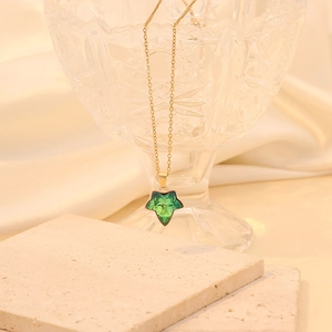 Détail du pendentif feuille dégradé vert sur une chaîne dorée élégante