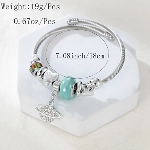 Detail of silver beaded bracelet with heart pendant and turquoise charms on a white base