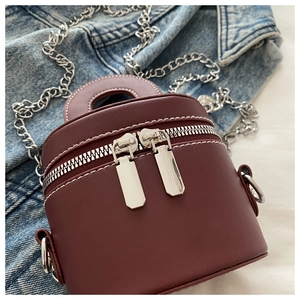 Vue détaillée du sac cylindrique rouge foncé avec chaînes argentées et coutures contrastées