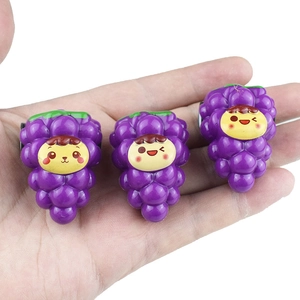 Detailed view of three purple grape hair clips with cute cartoon faces on a palm