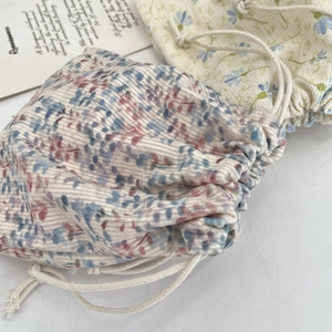Macro detail of floral corduroy drawstring storage bags with textured fabric and cotton ropes