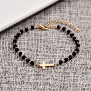 Minimalist beaded cross bracelet featuring faceted black beads and gold-plated pendant